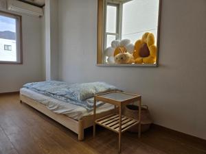 een slaapkamer met een bed en een raam met knuffels bij Kobe Youth Hostel in Kobe