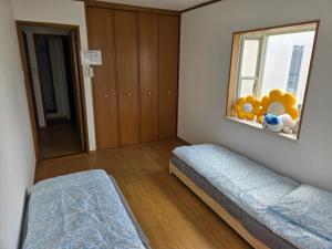 una camera con due letti e una finestra con animali di peluche di Kobe Youth Hostel a Kobe
