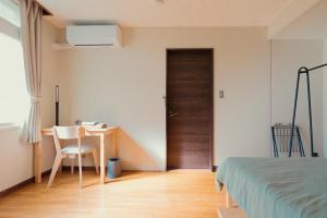 a bedroom with a bed and a desk and a door at ペコレラ学舎 Teacher House in Yakumo