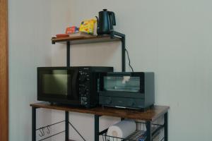 a television and a microwave sitting on a shelf at ペコレラ学舎 Teacher House in Yakumo