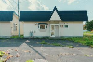 a white house with a black roof at ペコレラ学舎 Teacher House in Yakumo