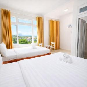 Una habitación de hotel con dos camas y una ventana. en Da Lat Ngoi Sao Viet, en Da Lat