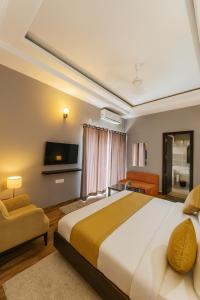 een slaapkamer met een groot bed en een televisie bij The Ruby Resort Vrindavan # Prime Location # Luxury Rooms # Near Prem Mandir # Restaurant # Big Lawn # Big Parking # By Nandan Group # in Vrindāvan