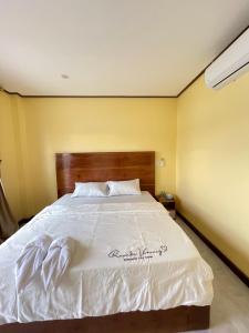 une chambre avec un grand lit blanc avec une tête de lit en bois dans l'établissement Tena Guest House, à Don Det