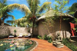 a garden with a small house with a pond of flowers at Casuarina Resort and Spa in Trou aux Biches