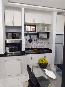 a kitchen with white cabinets and a glass table at La jarrie land in Mandanou