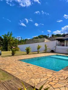 a swimming pool in a yard with a stone patio at Chácara Coração no Mato in Santa Isabel
