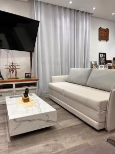 a living room with a white couch and a flat screen tv at Chácara Coração no Mato in Santa Isabel