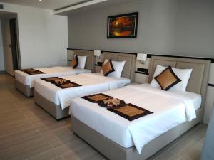 three beds in a room with white sheets at LN Hotel & Residence in Phnom Penh +53 photos