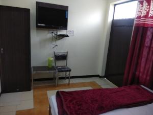 een slaapkamer met een bed en een flatscreen-tv bij Sant-I Hotel in Kānpur +16 foto's