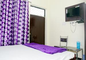 een slaapkamer met een bed met paarse gordijnen en een raam bij Sant-I Hotel in Kānpur