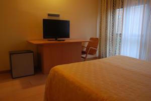 a bedroom with a bed and a desk with a television at Nuovo Hotel Vigevano in Vigevano