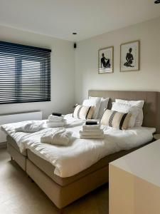 ein großes Bett mit weißen Laken und Kissen darauf in der Unterkunft Inspire Residence and private Wellness in Tongeren + 43 Fotos