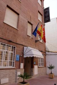 un edificio con banderas a un lado. en Hotel Cuatro Caños, en Alcalá de Henares