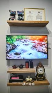 une télévision à écran plat sur une étagère avec une horloge dans l'établissement Kunba Homestay, à Hualien