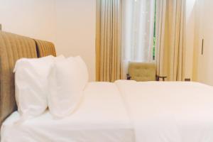 ein Bett mit weißen Laken und Kissen in einem Hotelzimmer in der Unterkunft Elysium Suites & Apartments in Accra + 9 Fotos