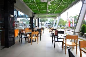 Un restaurante con sillas y mesas y una persona sentada en una mesa. en G'Sign Hotel Banjarmasin, en Sungai Lutus