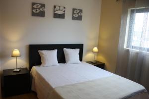 a bedroom with a large bed with two lamps and a window at Apartamento Mar e Sol in Ponta Delgada