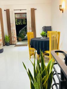 a dining room with a table and chairs and a plant at Moon View Homestay in Kamburugamuwa