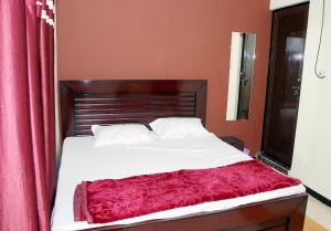 een slaapkamer met een bed met een rood gordijn bij Sant-I Hotel in Kānpur