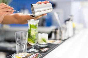 a person is pouring a green drink into a cocktail at Hotel Baltum in Albufeira