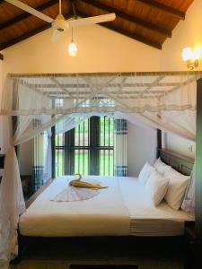 a bedroom with a white canopy bed with a window at Aaryana Lagoon in Tangalle
