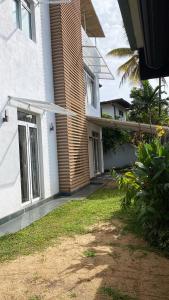 een wit huis met een deur en een grasveld bij Hagiazo Guest Inn Mirissa in Mirissa