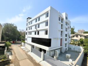 een wit gebouw met een hek ervoor bij Samrat Studios in Pune