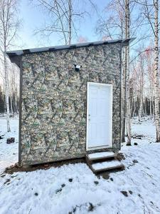 een stenen gebouw met een witte deur in de sneeuw bij Adventure Trail Cabin #9 in Houston +6 foto's