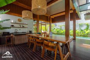 an open kitchen and dining room with a wooden table and chairs at Soocha B by Bukit Vista in Ungasan
