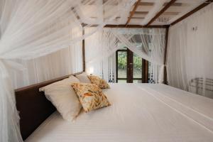 a bedroom with a bed with white drapes at Serene View Lodge in Unawatuna