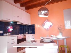 ボローニャにあるB&B Via Punta 8のオレンジ色の壁と白いキャビネット、テーブルが備わるキッチン
