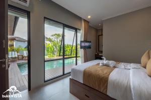 a bedroom with a bed and a view of a pool at Soocha C by Bukit Vista in Ungasan