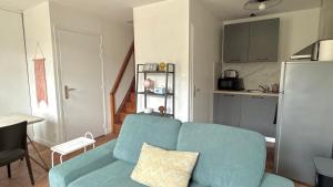 a living room with a blue couch and a kitchen at La Rollinoise in Valsonne +8 photos
