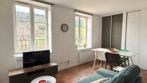 a living room with a couch and a table and windows at La Rollinoise in Valsonne