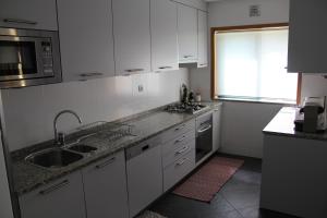 eine Küche mit weißen Schränken, einem Waschbecken und einem Fenster in der Unterkunft Quinta da Boavista - Moradia E in Caminha