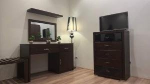 的黎波里فندق الجرات的房间里有一张带电视的梳妆台和一面带镜子的梳妆台。