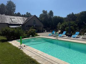 une piscine avec des chaises et une maison dans l'établissement Gite Les Quatre Alouettes, à Mazières-de-Touraine