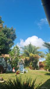 two chairs and a bird sitting in the grass at Quarto privativo em Araruama in Araruama