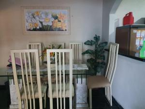 a dining room table and chairs with a table and a painting at Quarto privativo em Araruama in Araruama
