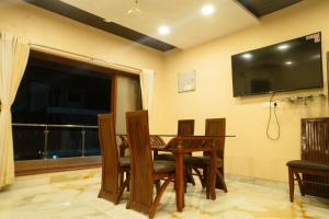 ein Esszimmer mit einem Tisch und einem Fernseher an der Wand in der Unterkunft Coral Bay Villa in Jāmb