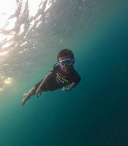 un uomo con occhiali da sole che nuota nell'acqua di NATA homestay a Banggai