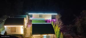 a house lit up at night with a neon sign at Oak Retreat Huts in Shimla +11 photos