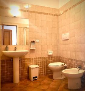 een badkamer met een wastafel, een toilet en een spiegel bij Villa Etruria Guest House in Pitigliano +17 foto's