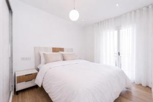 una camera da letto bianca con un letto bianco e una finestra di La Soleá Historic Center a La Herradura