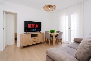 un soggiorno con TV e tavolo con sedie di La Soleá Historic Center a La Herradura