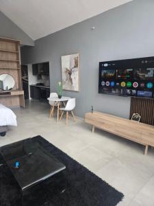 ein Wohnzimmer mit einer Couch und einem Fernseher an der Wand in der Unterkunft iThusi stream in Mbabane