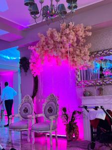 Una habitación rosa con dos sillas y una lámpara de araña. en Pensiunea Baroc, en Brasov