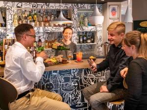 un grupo de personas sentadas en un bar en ibis Pontorson Baie Du Mont Saint Michel, en Saint-Georges-de-Gréhaigne