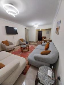 a living room with couches and a flat screen tv at Luxury Apartment In Sheikh Zayed - Jannah 2 Compound in Sheikh Zayed